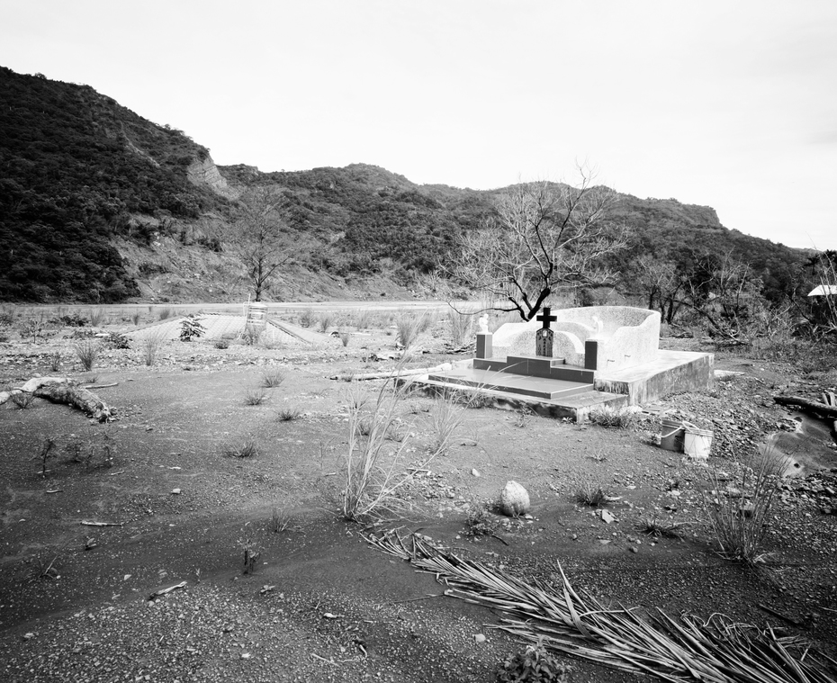 被沖毀的民宅與一旁新建的墳墓